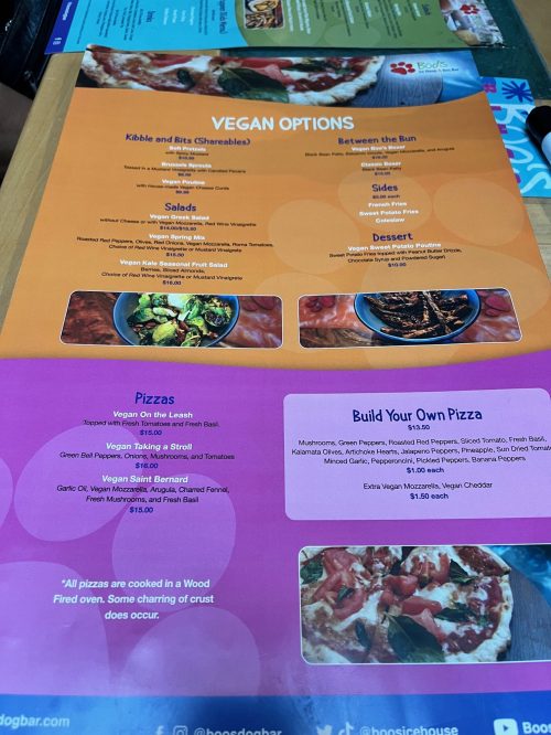 A colorful menu featuring vegan options, including salads, pizzas, and desserts, with descriptions and prices.