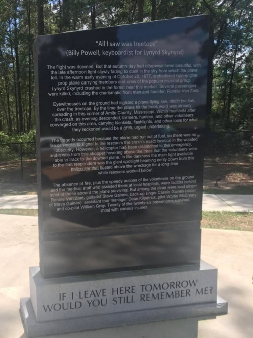 A memorial stone with text honoring Billy Powell, keyboardist for Lynyrd Skynyrd, in a wooded area.
