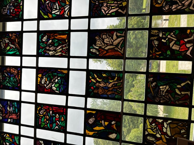 Colorful stained glass windows depicting various figures and nature scenes, with vibrant hues and intricate designs.
