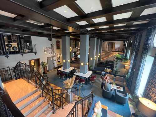 A spacious hotel lobby with modern decor, featuring a staircase, seating areas, and a bar in a stylish setting.