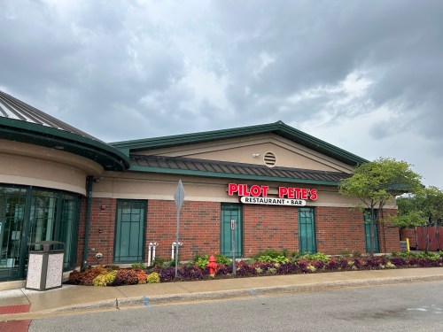 Exterior of Pilot Pete's Restaurant & Bar, featuring a brick facade and cloudy sky in the background.