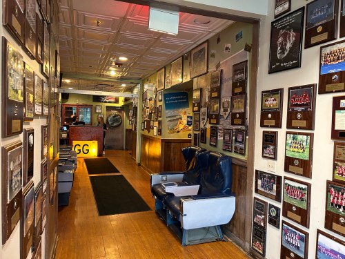 A hallway lined with framed plaques and photos, leading to a reception area with a seating area on the left.