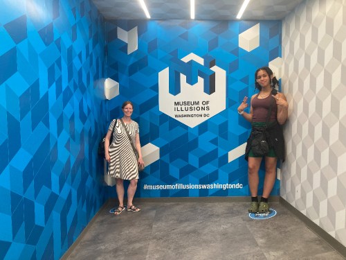 Two women pose in a colorful corner of the Museum of Illusions in Washington, DC, with playful expressions.