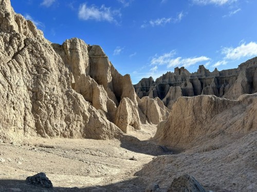A rugged landscape of eroded rock formations under a blue sky, showcasing dramatic cliffs and valleys.