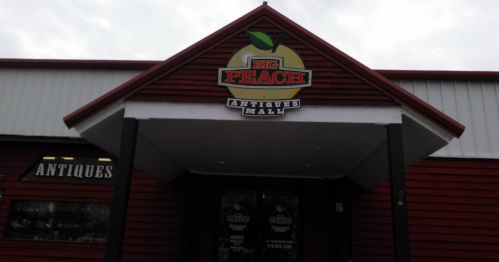 Sign for "Big Peach Antiques Mall" on a red building with a peaked roof and large entrance.