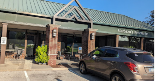 Exterior of Garozzo's Ristorante featuring a green roof, brick facade, and a parked car in front.