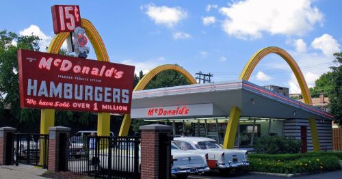 view of the original McDonald's franchise in Des Plaines, Illinois with vintage cars parked in front