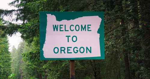 Welcome to Oregon sign surrounded by lush trees.