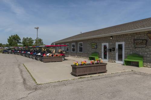 A stone building with a green roof, featuring parked motorcycles and flower planters in front.