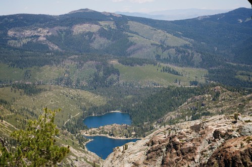 A scenic view of a mountainous landscape with a blue lake surrounded by lush green forests and rocky terrain.