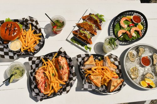 A spread of seafood, tacos, burgers, fries, and drinks on a table, featuring vibrant colors and various dishes.