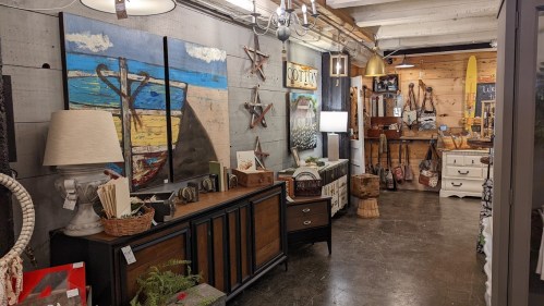 A cozy shop interior featuring rustic decor, artwork, and furniture, with wooden accents and warm lighting.
