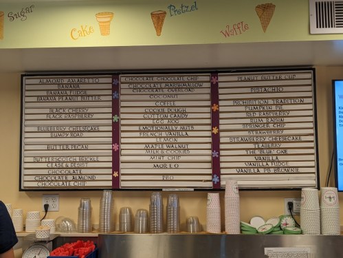 Menu board featuring various ice cream flavors and desserts, including chocolate, vanilla, and unique combinations.