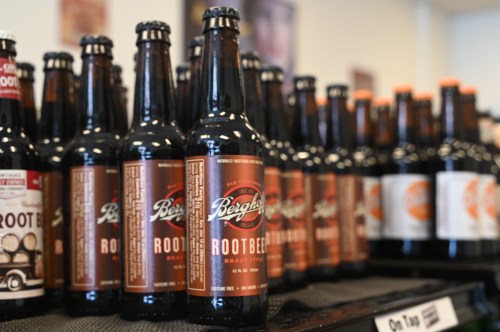 A display of glass bottles of Berg's Root Beer on a shelf, with various other soda bottles in the background.