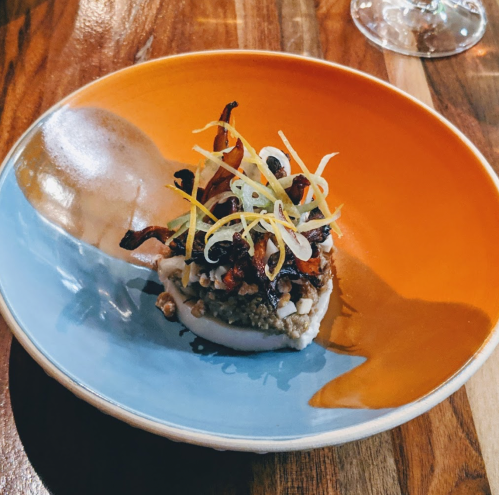 A colorful plate featuring a gourmet dish topped with crispy vegetables and garnished with thinly sliced onions.
