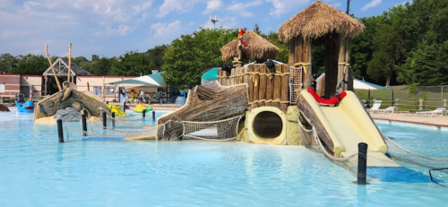 A water park featuring a large, themed play structure with slides and a shallow pool area under a blue sky.