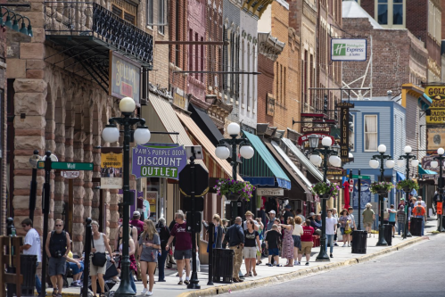 A bustling street scene with shops, pedestrians, and decorative street lamps in a historic downtown area.