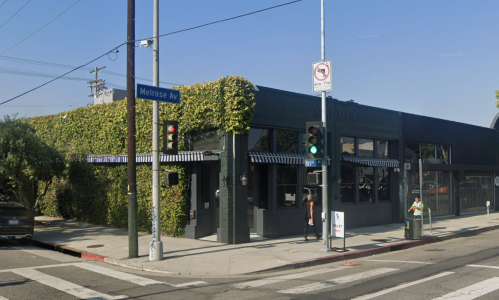 A street corner view of a green-covered building on Melrose Avenue with traffic lights and a no parking sign.
