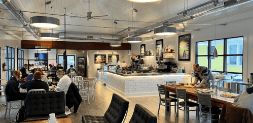 A modern café interior with seating areas, a counter, and patrons enjoying their time. Bright and inviting atmosphere.