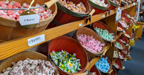 Baskets filled with colorful candies in various flavors, neatly arranged on wooden shelves.