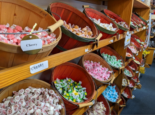 Colorful candy displayed in wooden baskets on shelves, featuring various flavors like cherry, mint, and lemon.