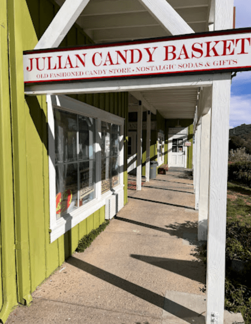 Sign for "Julian Candy Basket," an old-fashioned candy store with a green exterior and a welcoming entrance.
