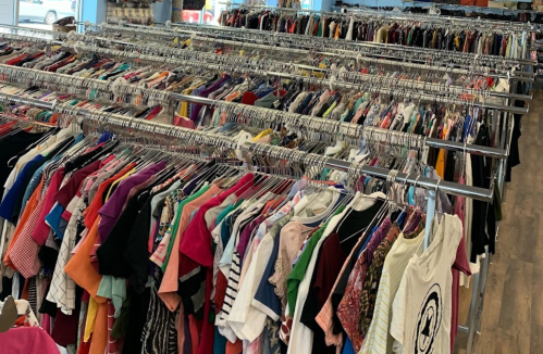 A clothing rack filled with a variety of colorful shirts and tops in a retail space.
