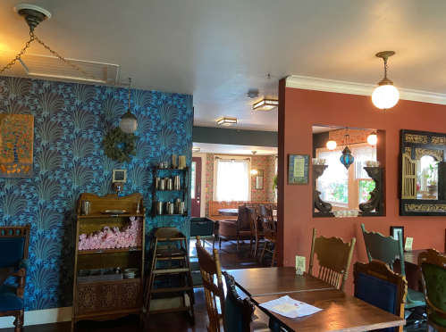 Cozy restaurant interior featuring patterned wallpaper, wooden furniture, and warm lighting.