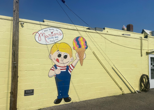 A colorful mural of a cartoon boy holding an ice cream cone on a yellow wall, promoting a dairy bar.