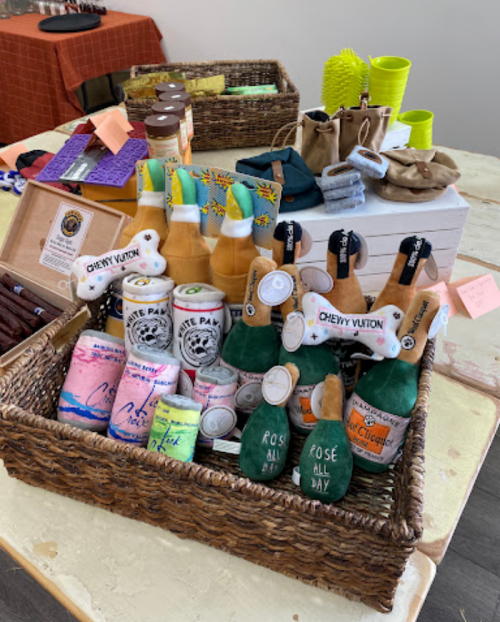 A basket filled with colorful dog toys and treats, including bottles and cans designed for pets.