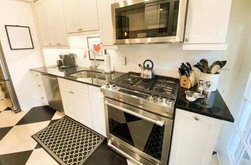 A modern kitchen with black and white checkered floor, stainless steel appliances, and a sleek countertop.