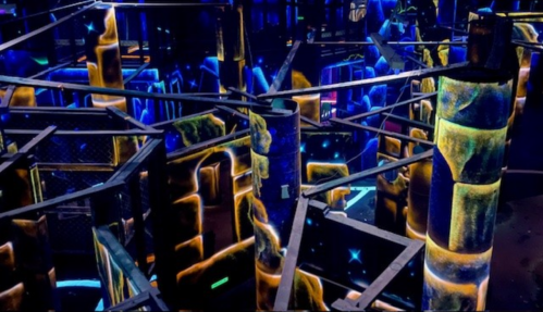 A colorful maze with glowing walls and pillars, illuminated in blue and yellow lights, creating a vibrant atmosphere.