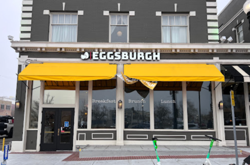 Exterior of Eggsburgh restaurant with yellow awnings, featuring large windows and a sign for breakfast, brunch, and lunch.