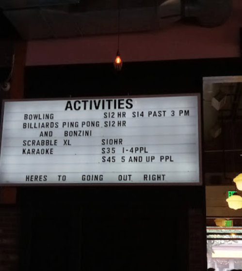 Sign listing activities and prices: Bowling, Billiards, Scrabble, and Karaoke, with various rates for each.
