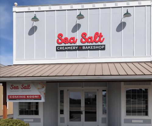 Exterior of a building with a sign reading "Sea Salt Creamery + Bakeshop" and a banner that says "Coming Soon!"