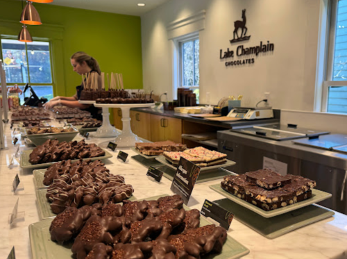 A display of assorted chocolates and confections at Lake Champlain Chocolates, with a staff member preparing treats.