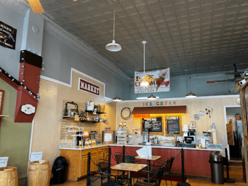 Interior of a cozy ice cream shop with a counter, menu, and seating area, featuring a vintage decor style.