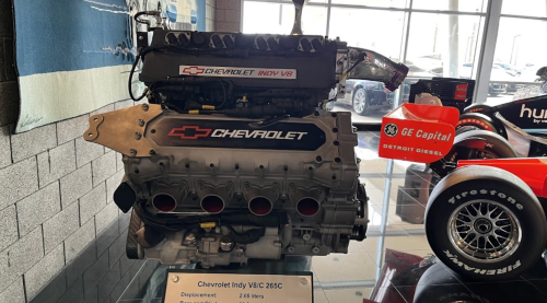 A Chevrolet Indy V8 engine displayed on a stand, showcasing its sleek design and performance features.