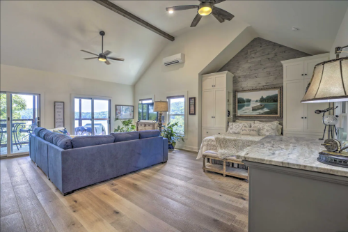 Cozy living space with a blue sofa, wooden floors, and large windows showcasing a scenic view.