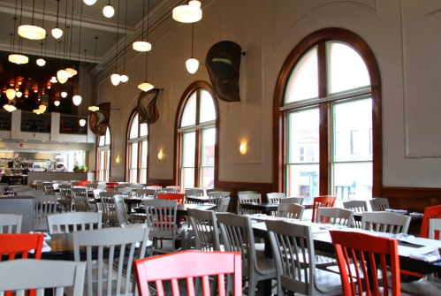 Bright restaurant interior featuring large windows, colorful chairs, and modern lighting fixtures.