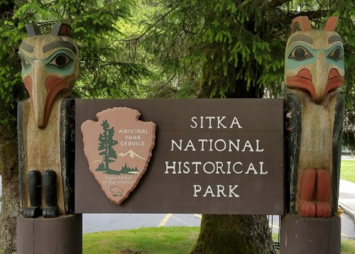 Sign for Sitka National Historical Park featuring totem poles and the National Park Service emblem.