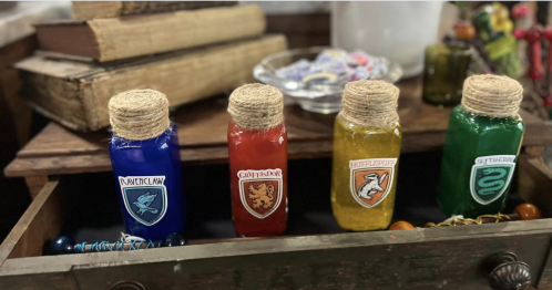 Four colorful potion bottles labeled for Hogwarts houses: Ravenclaw, Gryffindor, Hufflepuff, and Slytherin.