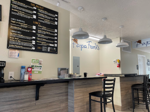 Interior of a café with a menu board, counter seating, and light fixtures. The name "Papa Frank's" is visible.
