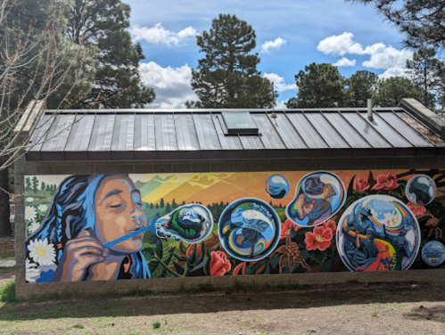 A colorful mural depicting a girl blowing bubbles, surrounded by nature and vibrant flowers against a scenic backdrop.