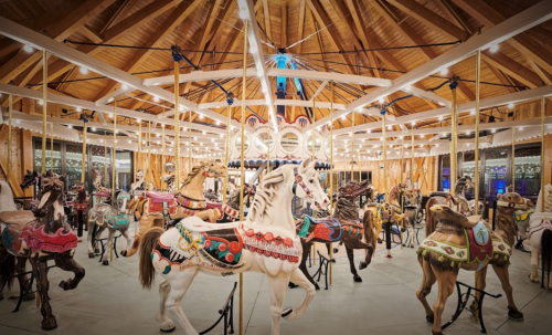 A beautifully lit carousel with intricately designed horses inside a wooden structure.