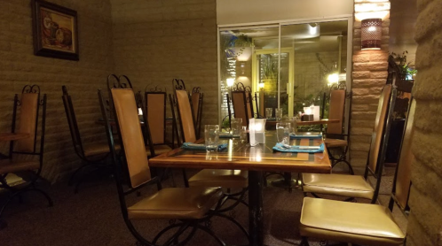 Empty restaurant interior with stacked chairs, tables set for dining, and soft lighting creating a cozy atmosphere.