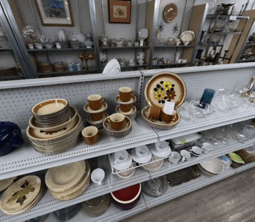 A display of various dishware, including plates, cups, and glassware, arranged on shelves in a store.