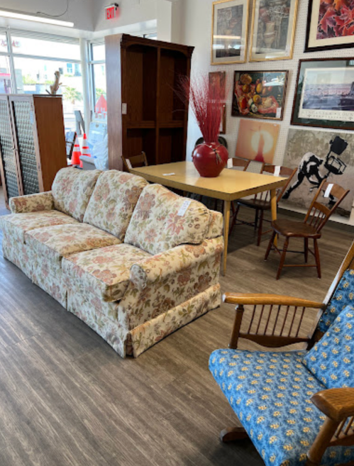 A floral-patterned sofa in a room with a dining table, chairs, and various artworks on the walls.