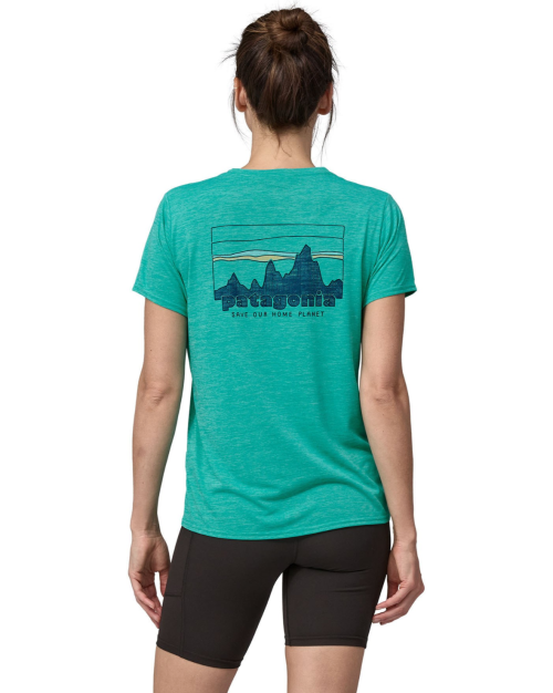 A woman wearing a teal Patagonia t-shirt with a mountain graphic on the back, paired with black shorts.
