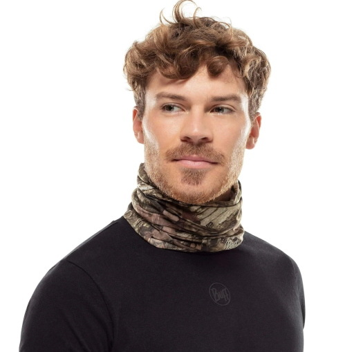 A man with curly hair wearing a camouflage neck gaiter and a black shirt, looking confidently to the side.